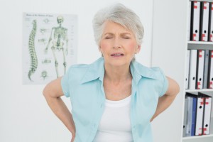 Senior woman women back pain standing medical office grimace hurt hurts
